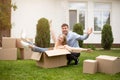 Silly young couple playing with carton box near new house on moving day