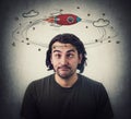 Silly young man makes funny dumb faces with crossed eyes. Body language emotional reaction. Dizzy daydreaming, stars and rocket Royalty Free Stock Photo