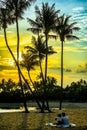 Siloso Beach with couple relaxing under coconut trees during sunset at Sentosa Island, Singapore. Royalty Free Stock Photo