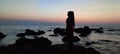 Silouhette of a hijabi girl on a beautiful beach with rocks after sunset