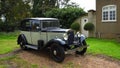 Vintage 1933 Austin 12/4 Harley parked by cottage in sunshine.