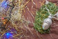 The silver acorn ceramic Christmas decoration on the branch of spruce with the colorful garland and tinsel.