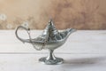 Silver aladdin`s lamp on a white wooden background. Ramadan concept.