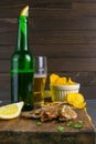 Silver Amber Fish with pepper with beer, lemon and potato chips on dark wooden board. Snack on fish with beer. Front views, close-