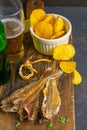 Silver Amber Fish with pepper with beer, lemon and potato chips on dark wooden board. Snack on fish with beer. Front views, close-