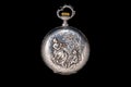 Silver antique pocket watch with a closed lid on an isolated black background. Round retro pocketwatch with a pattern of