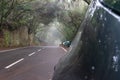 Silver auto in creepy forest and foggy route in a journey to scape, driving with safety in an asphalt mountain road. Car parked