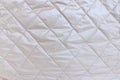 Silver background of quilted fabric, close up