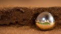 The silver ball lies on the brown muddy ground in the sand. A lost piece of jewelry is lying on a deserted land. Generated AI.