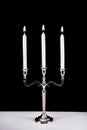 Silver baroque candlestick with three white paraffin candle burning on desk and black background Royalty Free Stock Photo