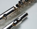 A silver bass flute lying on a white reflective surface Royalty Free Stock Photo