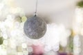 Silver bauble hanging on unfocused background with shiny sparkling garland lights and bokeh. Christmas tree toys and New Year Royalty Free Stock Photo