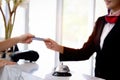 Silver bell on hotel reception service desk with blurred background of female receptionist hand reaching out for receiving credit Royalty Free Stock Photo