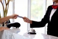 Silver bell on hotel reception service desk with blurred background of female receptionist hand reaching out for receiving credit Royalty Free Stock Photo