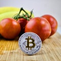 Silver bitcoin coin near vegetables