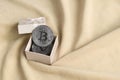 The silver bitcoin lies in a small orange gift box with a small bow on a blanket made of soft and fluffy light orange fleece Royalty Free Stock Photo