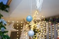 Silver and blue baubles hanging on unfocused background with shiny sparkling garland lights and bokeh. Christmas tree toys Royalty Free Stock Photo