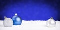 Silver and blue Christmas baubles on snow, blue background Royalty Free Stock Photo