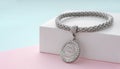 Silver bracelet with flower shape pendant on pastel colors background with copy space Royalty Free Stock Photo