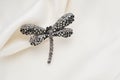 Silver brooch shaped like a dragonfly with small diamonds