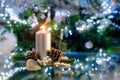 Silver burning candle with christmas decoration of fir tree and cones, in front of a green Christmas tree with bokeh Royalty Free Stock Photo