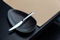 Silver butter knife on black bowl on the wooden table with leather mat. For Fine Dining and European food with copy space Royalty Free Stock Photo