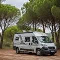 A silver camper van is parked on a dirt pathway surrounded by lush, green Royalty Free Stock Photo
