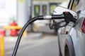 Silver mettalic color car refueling on night gas station - close-up with selective focus and blurry background