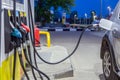 Silver mettalic color car refueling on summer night gas station - close-up with selective focus and blurry background