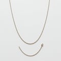 Silver chain necklace with a broken segment lies on a plain white background. The Royalty Free Stock Photo