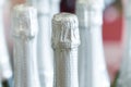 Silver champagne bottle necks and top caps at standing the light background in liquor store.