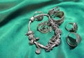 Silver charm bracelet with charms and rings on the green silk Royalty Free Stock Photo
