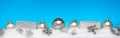 Silver Christmas balls with xmas gift boxes in a row on snow.Blue background Royalty Free Stock Photo