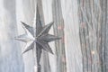 Silver Christmas star with many sparkles against a light textile curtain. Home decoration for a family holiday with copy space Royalty Free Stock Photo