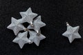 Silver Christmas star ornaments om dark glittery background with copy space