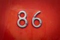 Silver chrome door number 86 eighty sic screwed onto wood painted bright red