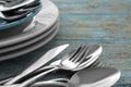 Silver clean spoons, forks and knives with plates on old light blue wooden table, closeup Royalty Free Stock Photo