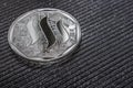 The silver coin of the Steem cryptocurrency on a gray background