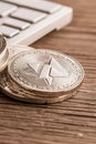 Silver coins stack sits near keyboard on wood. Symbol on coins represents cryptocurrency trading concept. Royalty Free Stock Photo