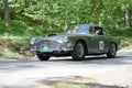 Silver color Aston Martin DB4 classic car from 1960 driving on a country road