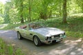 Silver color Aston Martin Volante classic car from 1984 driving on a country road