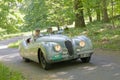 Silver color Jaguar XK120 Alloy classic car from 1949 driving on a country road