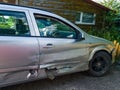 Silver colored car with scratches and extensive damage to the doors