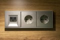 Silver colored European power plug outlet with USB port charging on a wooden wall