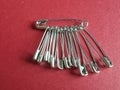Silver colored safety pins of various sizes on red paper Royalty Free Stock Photo