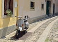 Silver colored vintage Vespa PX scooter parked on an ancient cobblestone road in the town Royalty Free Stock Photo