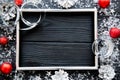 Silver cones, silver frame, silver ribbons and red Christmas balls on black table. Space for text.