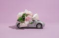 Silver convertible small car model with flowers on a purple background. The concept of delivery of flowers and gifts for the