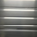 Silver corrugated metal panel featuring horizontal ridges. The surface displays a brushed texture Royalty Free Stock Photo