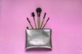 Silver cosmetic bag with makeup brushes on a pink background. Set of decorative accessories for woman. Top view, flat lay Royalty Free Stock Photo